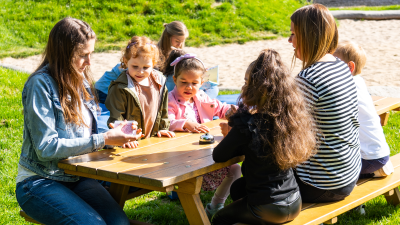 zwei Erzieherinnen mit vier Kindern an Tisch